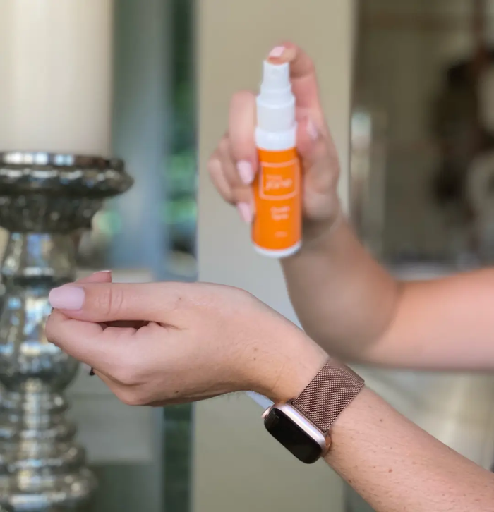 Hand holding Basic Jane Awake CBD Pain Spray with a refreshing citrus scent, designed for convenient, targeted topical application.