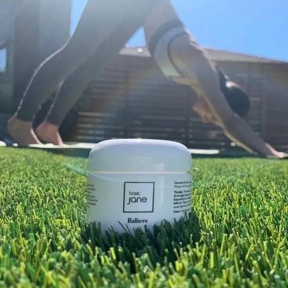 Person doing yoga.  Basic Jane Relieve CBD Cream for post-yoga muscle care, supporting relaxation and recovery after stretching, exercise, and movement.